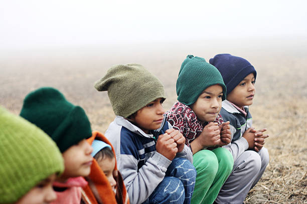Three Poor Children Sitting in Winter Season Outdoor Portrait.
